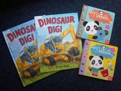 Two copies of Dinosaur Dig! by Penny Dale and two Noodle children’s books—Noodle Loves the Beach and Noodle Loves To Cuddle, each featuring charming panda illustrations—are laid out on a blue carpeted floor.